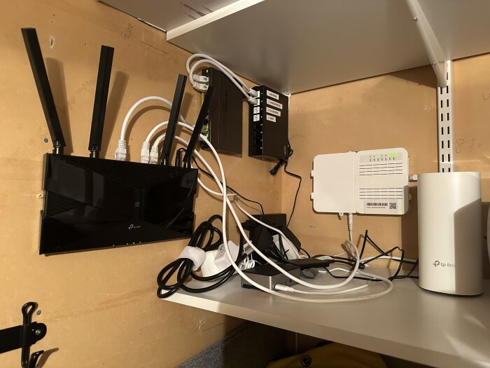 Väggmonterad keystone patchpanel och nätverksutrustning med kablar anslutna i ett hus, fotat från ett nätverksrum.