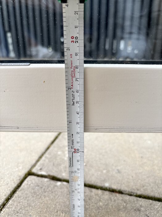 Tumstock visar avståndet 12 cm från golvplatta till dörrens underkant i öppet läge, reflekterar över om reglar kan placeras direkt på plattan.