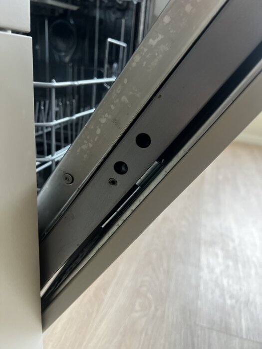 Närbild av insidan på en diskmaskinslucka med synliga skruvhål där monteringsproblem beskrivits i texten.