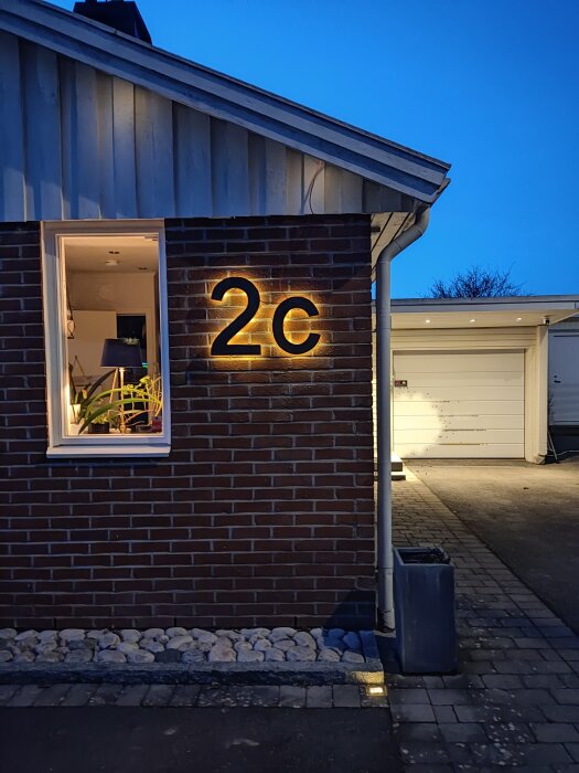 Vägg med stora träbokstäver "2c" belysta med LED-ljus mot mörk bakgrund.