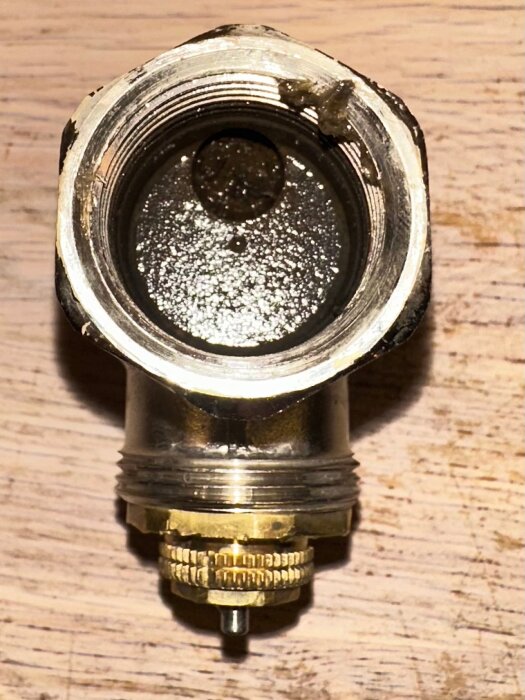 Inre sikt av en termostatventil med magnetitansamling, vilket hindrade korrekt vattenflöde och cirkulation innan bytet till en ny ventil.