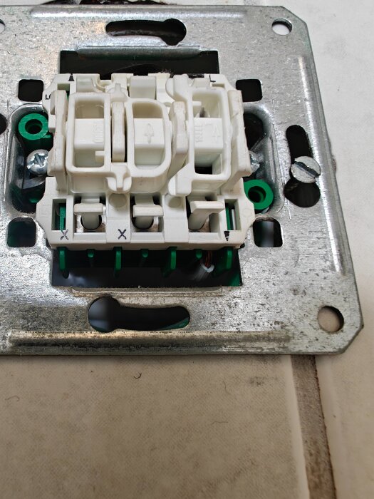 Två plastbrytare monterade på en metallram för elektrisk installation, med synliga skruvar och kabelanslutningar.