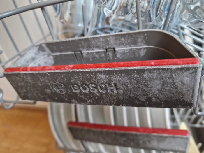 Diskmaskinsinsida med märkeslogotyp, visar kalkavlagringar och rengöringsbehov i en Bosch diskmaskin.