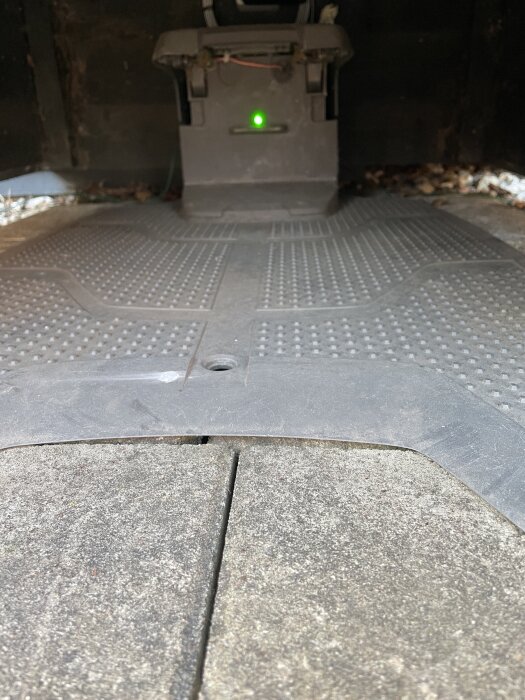Bild av en garagegolvmatta med en synlig grön lampa som lyser stadigt, vilket ger intryck av fungerande utrustning.