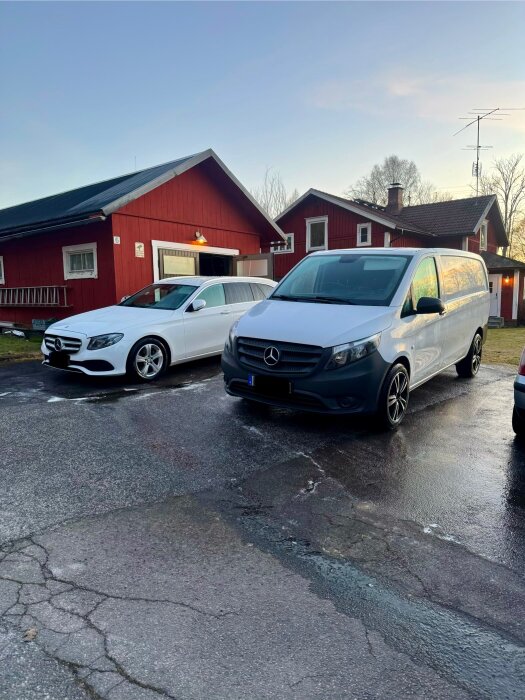 Två nytvättade Mercedes-bilar, en vit kombi och en silver skåpbil, parkerade framför röda hus.