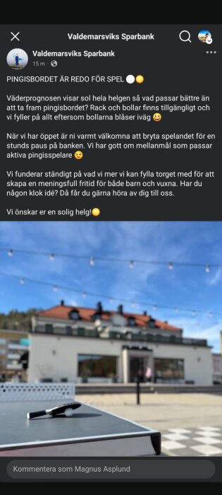 Pingisbord med racket och boll utanför en bankbyggnad under en blÄ himmel med ljusslinga.