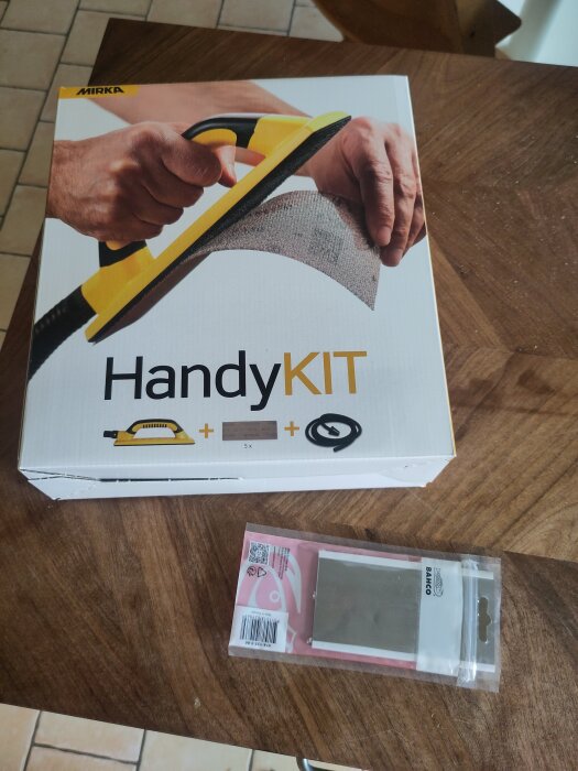 Mirka HandyKIT på en träbänk, tillsammans med en oanvänd Bahco-sickel i förpackning, redo för slipning och behandling med hårdvaxolja.