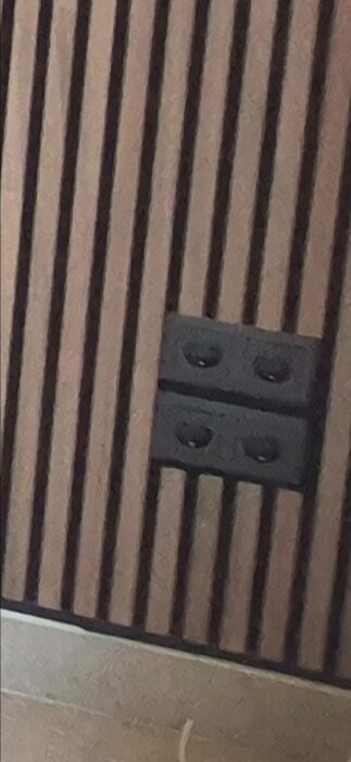 Vägg med träpanel och två svarta eluttag.