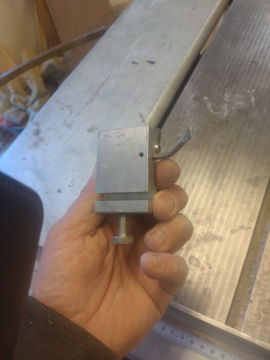 Hand håller en klump i aluminium med ståldel, del av konstruktion till Luna W69.