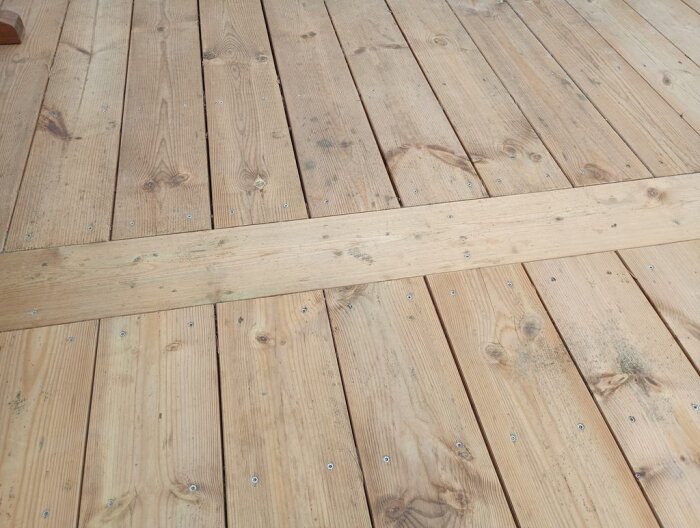 Ljusbrun träaltan under tak, fuktfläckar synliga efter en regnig vinter.
