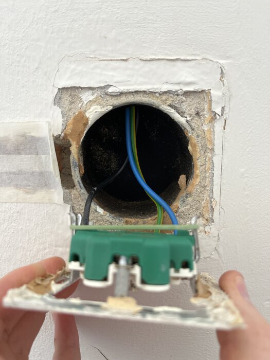 Elektrisk dosa i väggen med synliga ledningar, del av renoveringsprojekt för att fördela elektricitet till ny rumindelning.