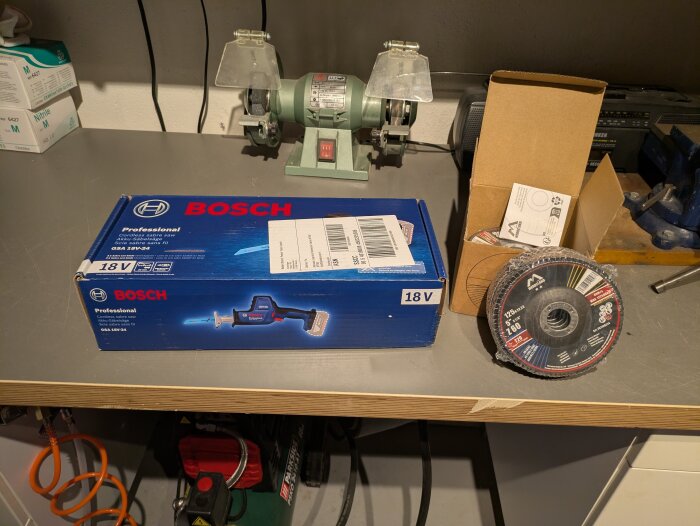 Förpackning med Bosch tigersåg och en kartong med lamellrondeller på en verkstadsbänk.