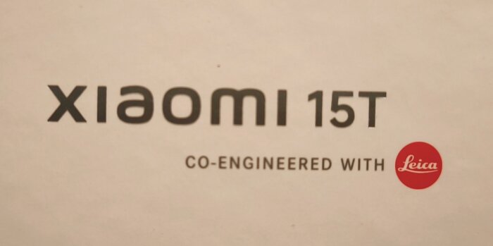 Text på mobilförpackning, "Xiaomi 15T, co-engineered with Leica", där Leica-loggan syns i röd cirkel.