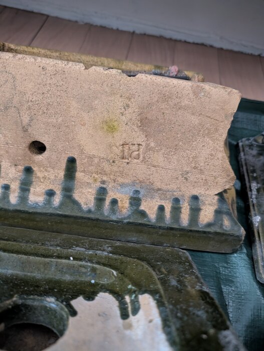 Delar av en kakelugn med grön glasyr och inristningen "fd" på en del. Förmodligen från ett hus byggt 1904.