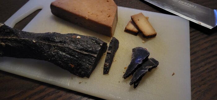 Jeans cheese and smoked moose meat on a cutting board, knife beside.