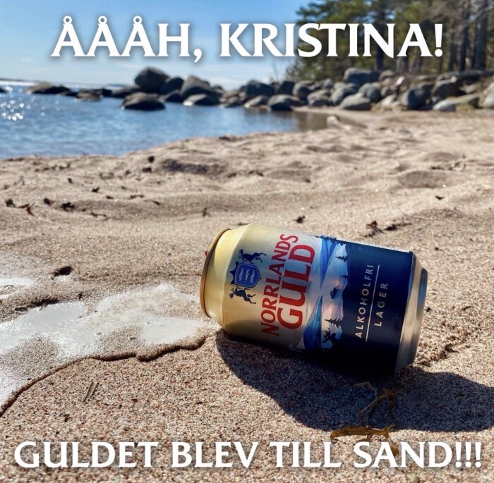 Burk med alkoholfri Norrlands Guld lager liggande på sandstranden vid sjön, med träd och stenar i bakgrunden. Text: "ÅÅÅH, KRISTINA! GULDET BLEV TILL SAND!!!