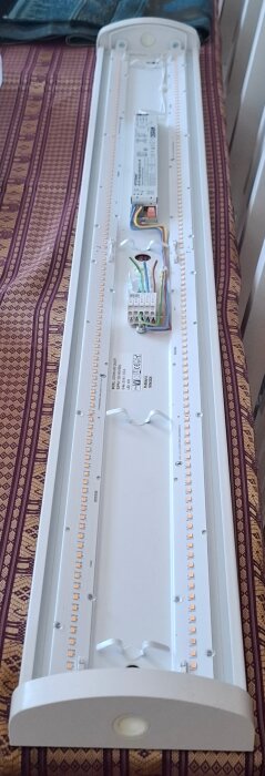 LED-armatur med avlång konstruktion, synliga dioder och kablage. Text visar "Ledwin 40w on/off". Bakgrund mönstrad duk.