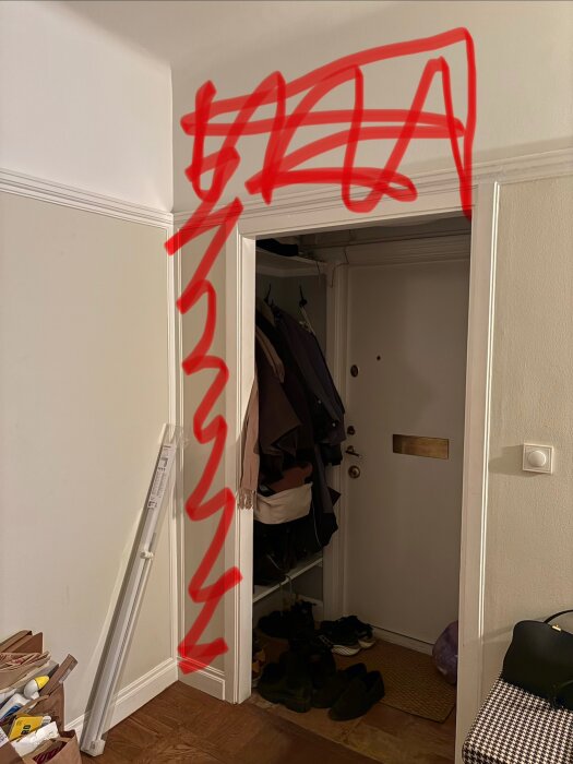 Väggen vid dörröppningen i en hall markerad med röd färg för rivning under renovering.