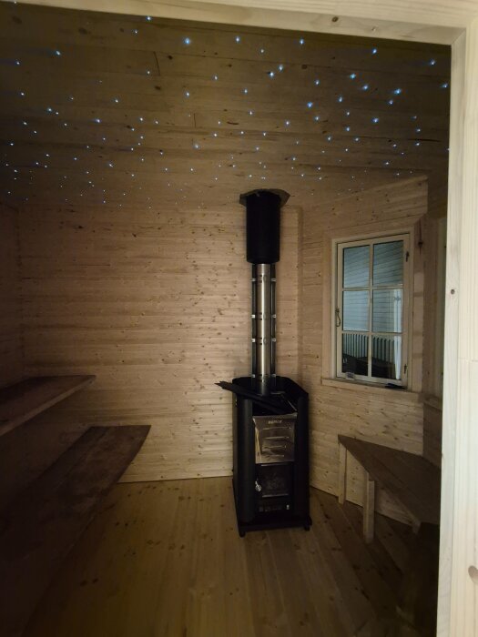 Bastu med installerad stjärnhimmel i taket, vedeldad kamin, trävita väggar och bänkar. Stjärneffekten skapas av fiberoptik.