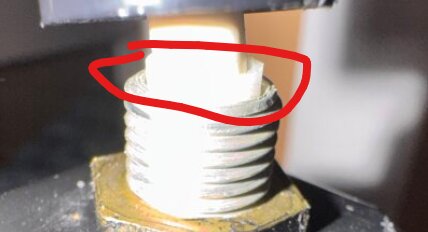 Närbild av en lampas lamphållare med fokus på sockeln, där en del av den isolerade tratten syns markerad med en röd cirkel.