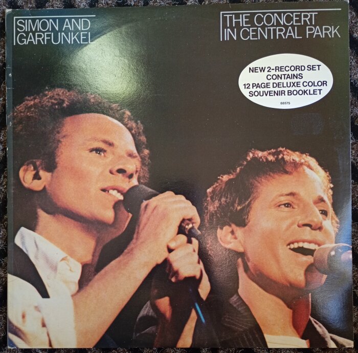 Omslag av Simon & Garfunkels livealbum "The Concert in Central Park" med Art Garfunkel och Paul Simon som sjunger i mikrofoner.
