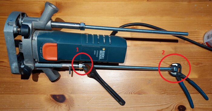 Anpassad bordfräsinstallation med Black & Decker fräs, visar två gängstänger, muttrar, polygriptång och justering av höjdinställning på träbord.