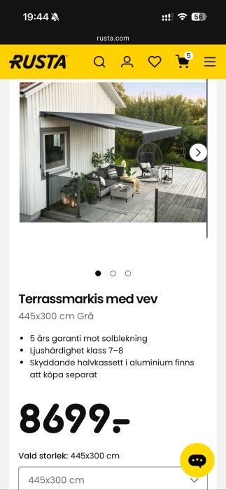 Grå terrassmarkis monterad på vit fasad, skyddad uteplats med sittmöbler och växtdekorationer, produktsida från Rusta.