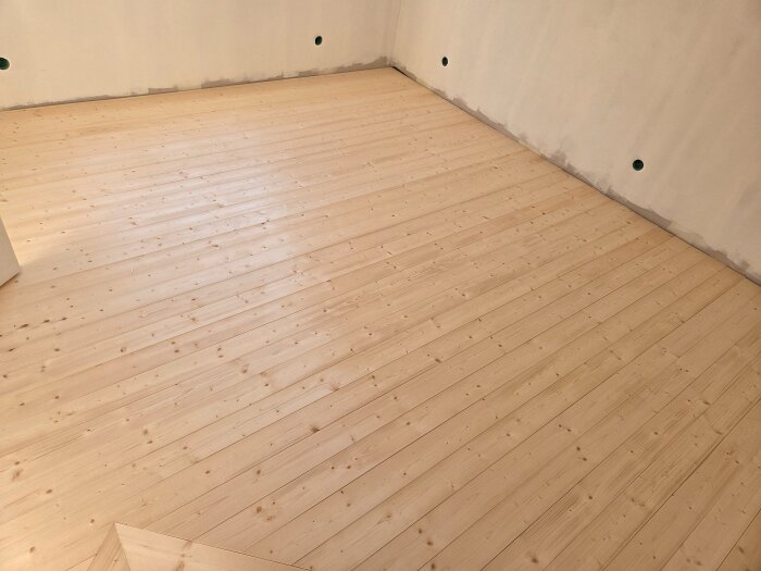 Nytt grangolv i sovrum, vissa brädor kupade under torkning. Slipning behövs för att jämna ut ytan och skapa ett gammaldags skurgolv utan vassa kanter.