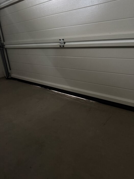 Glapp under garageporten och fuktigt golv inuti garaget.