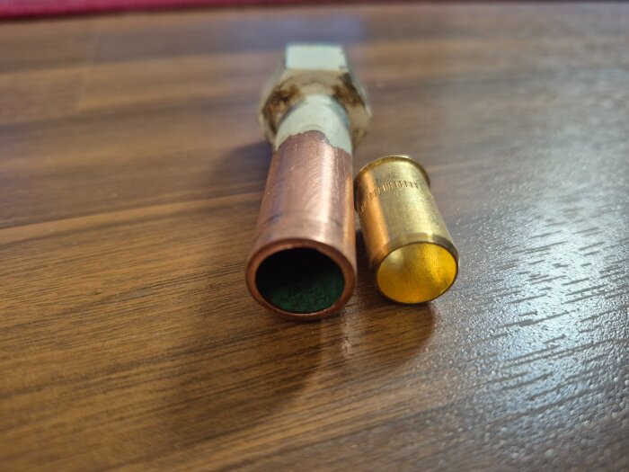 Kopparrör bredvid en gul stödhylsa på ett träbord, del av diskussion om montering på 16 mm rör.
