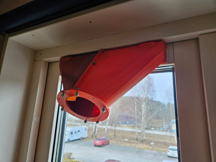 3D-printad adapter i röd PLA-plast monterad ovanför ett fönster för att mäta luftflöde genom spaltventiler.