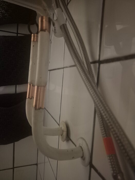 Ett metallrörsystem i en vitkaklad miljö, där en del av röret är bart medan andra delar ser ut att ha blivit rengjorda från färg.