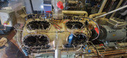 Motordel med fyra cylindrar under reparation i ett verkstadsutrymme.