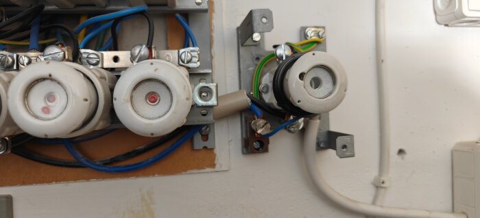 En elektrisk central med säkringshållare och kablar inklusive blå PEN-ledare, samt grön-gula och svarta kablar kopplade till anslutningar.