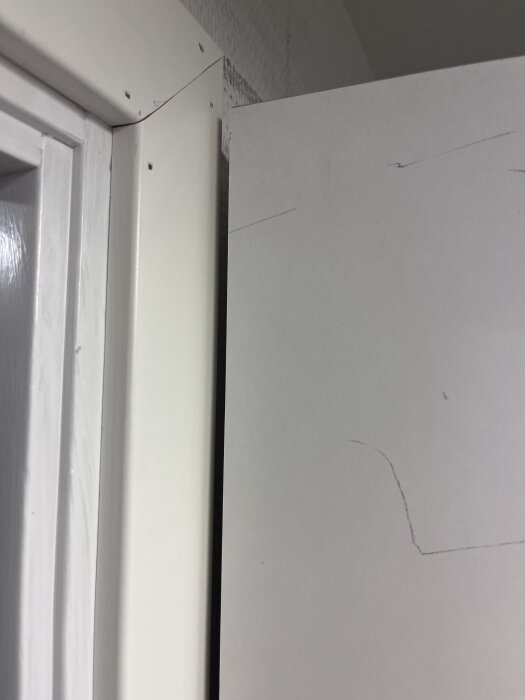 Garderobsdörr och dörrkarm med tillskurna foder för att passa ihop, synliga linjer och små hål i fodret.