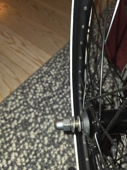 Närbild på en cykelaxel med två brickor på utsidan av framgaffeln, inlägg diskuterar placering av dubbelbrickor.