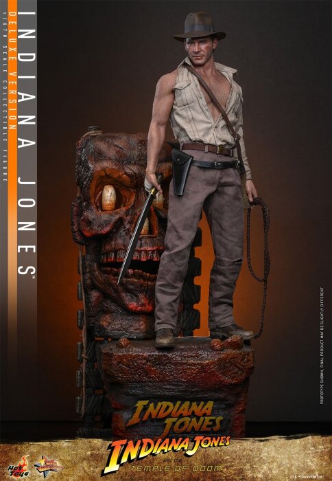 Actionfigur av äventyrare i hatt och läderjacka, står mot en detaljerad bakgrund med skalle och text "Indiana Jones".