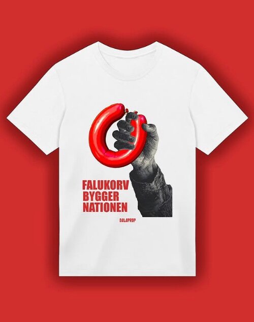 En vit t-shirt med en bild av en hand som håller en falukorv och texten "Falukorv bygger nationen".