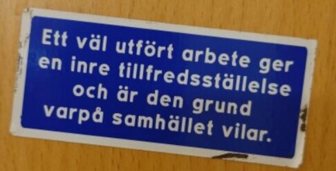 Ett blått klistermärke med texten: "Ett väl utfört arbete ger en inre tillfredsställelse och är den grund varpå samhället vilar.