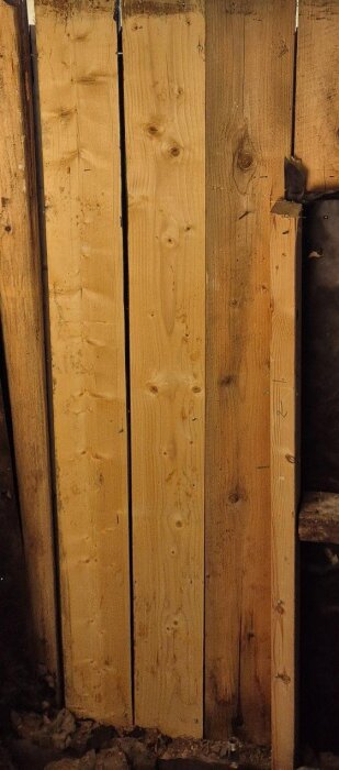 Blöta träpaneler med tecken på vatteninträngning i nederkanten, vilket orsakar fuktproblem på insidan av väggen.