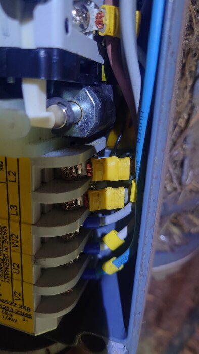 Närbild på elektronisk krets med flera anslutna kablar och komponenter, inklusive gul märkning och synliga skruvar.