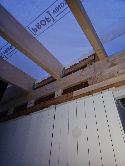 Limträbalkar under byggnation, inspekteras för säkerhet innan installation av plåt, isolering och innertak.