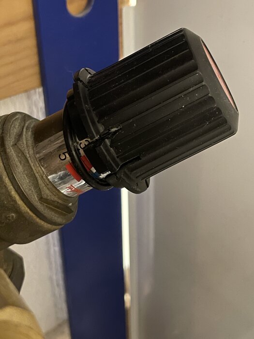 Svart vred på flödesregulator med felplacerad o-ring under, på röranslutning i värmesystem.