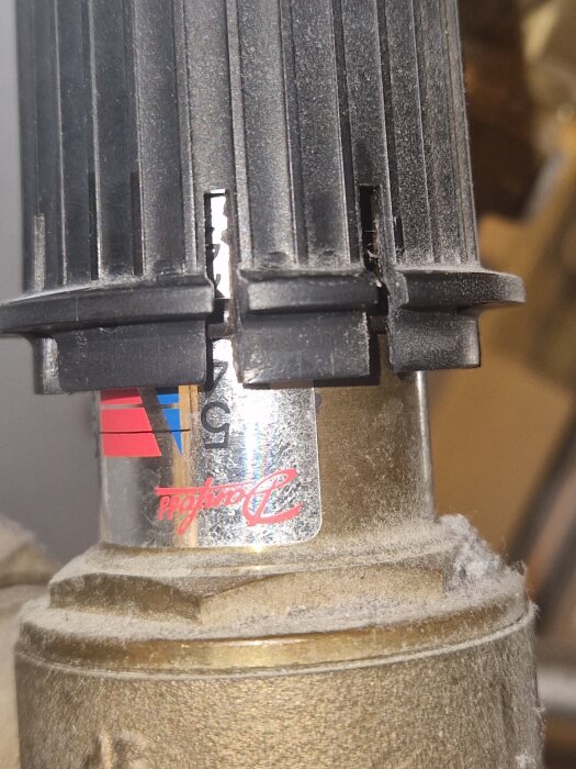 Del av en ventil med en etikett som har logotypen "Danfoss". Den svarta plastdelen saknar en O-ring enligt texten.