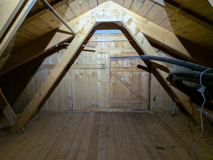 Kallvind med träpanel och träbjälkar, synliga ledningar och genomföring, del av diskussion om isolering och ventilation i ett 70-talshus.