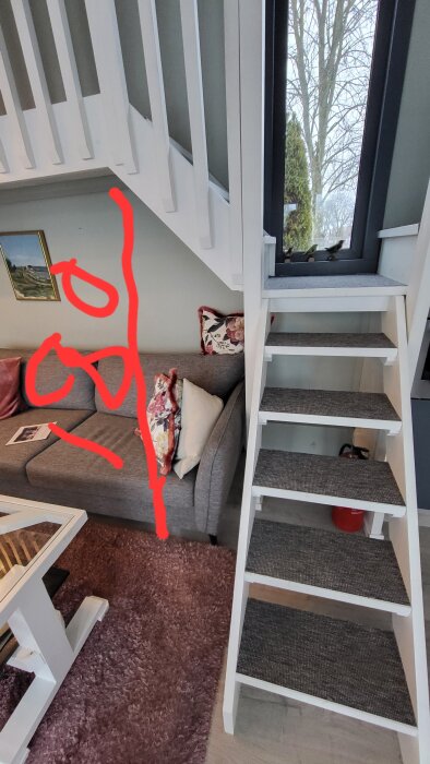 Grå soffa med färgglada kuddar under en vit trappa, bredvid ett stort fönster. Röda linjer markerar ytor på bilden.