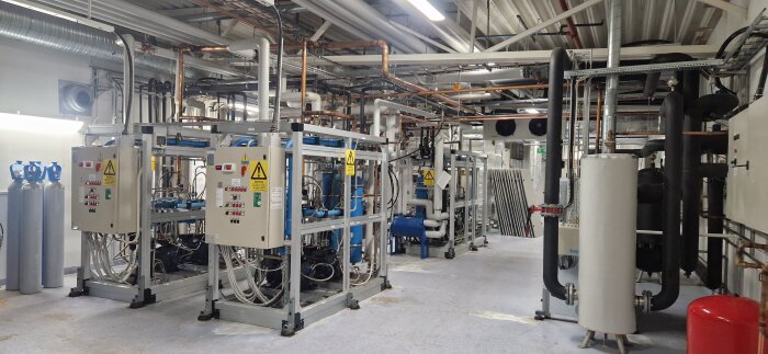 Industriell maskin- och rörinstallation i teknikutrymme.