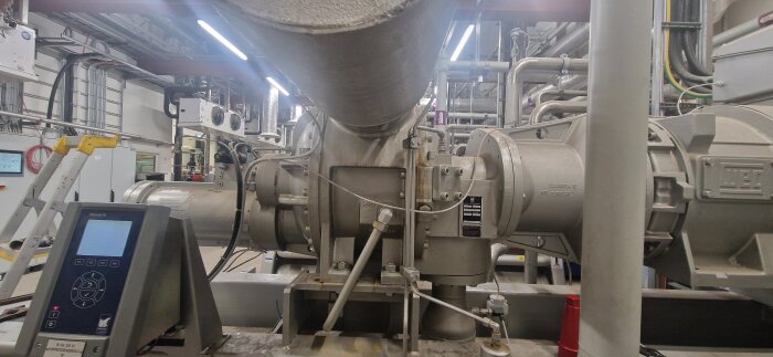 Industriell installation med ett stort rörsystem och teknisk utrustning i en fabriksmiljö.