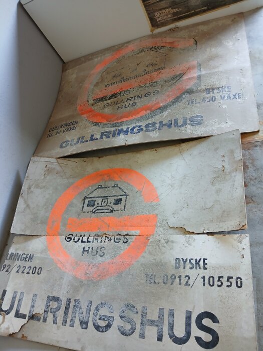 Vintage skyltar från 1966 med texten "Gullringshus" och telefonnummer, placerade mot en vägg.