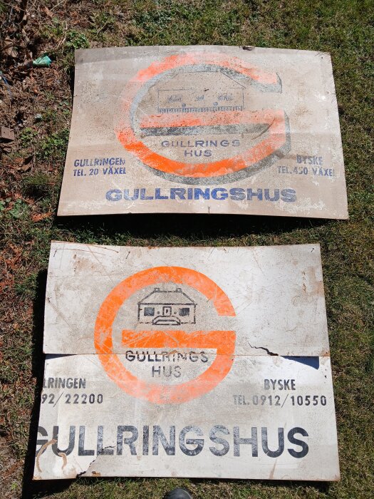 Två gamla "Gullringshus" skyltar från 1966 ligger på gräs, med orange och svart text och ett husmotiv i mitten.